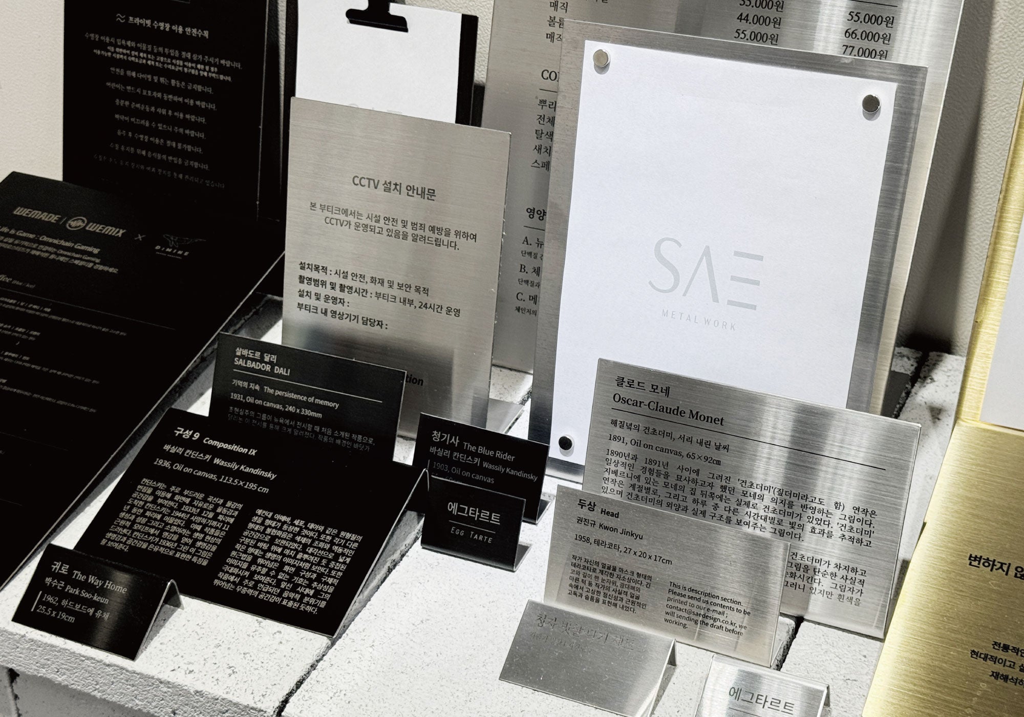 Display of custom metal signage, engraved tags, and branded plates by SAE METAL WORK, showcasing minimalist typography and industrial materials in a refined presentation.