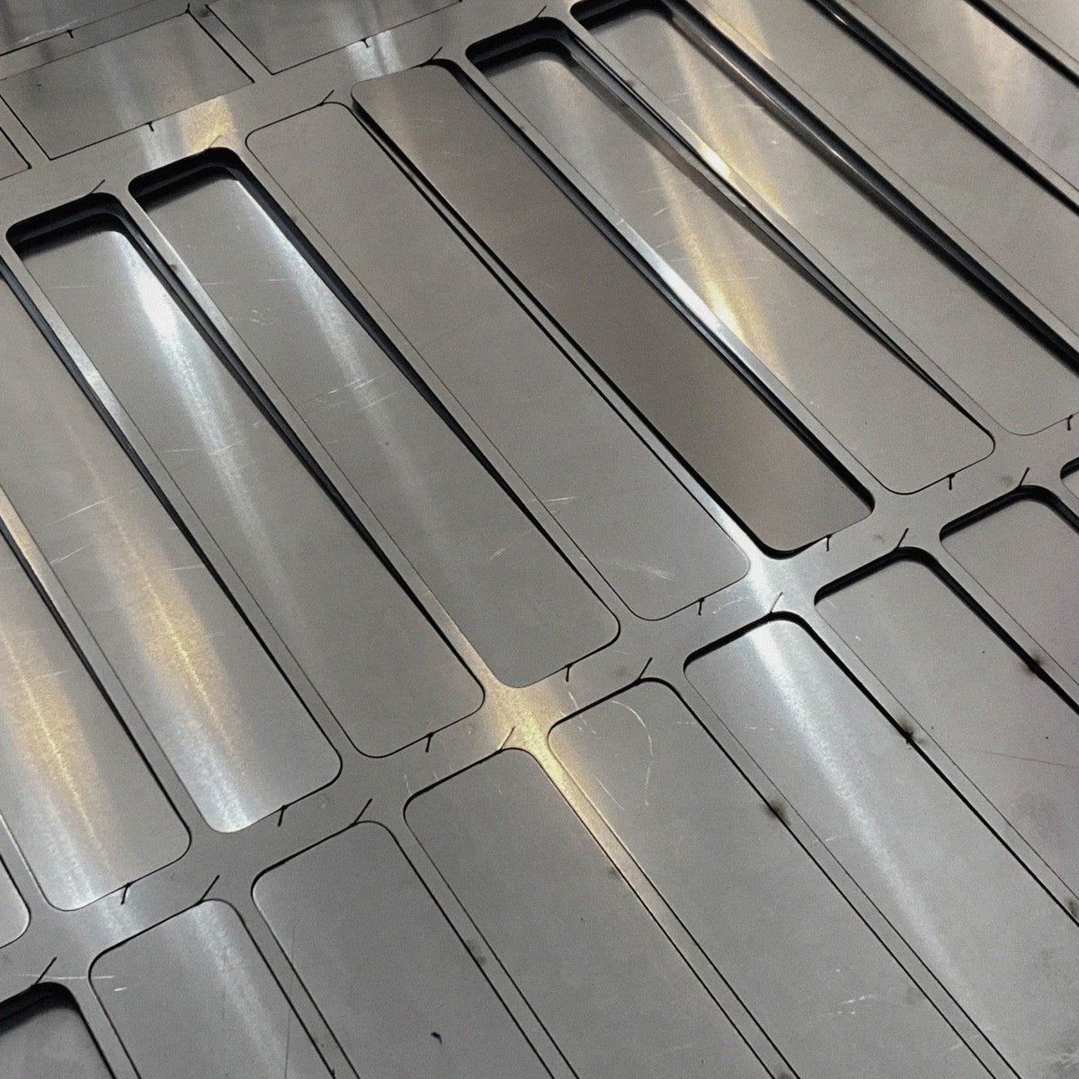 Precision-cut stainless steel components displayed in parallel rows, showcasing uniformity and structural balance after laser processing.