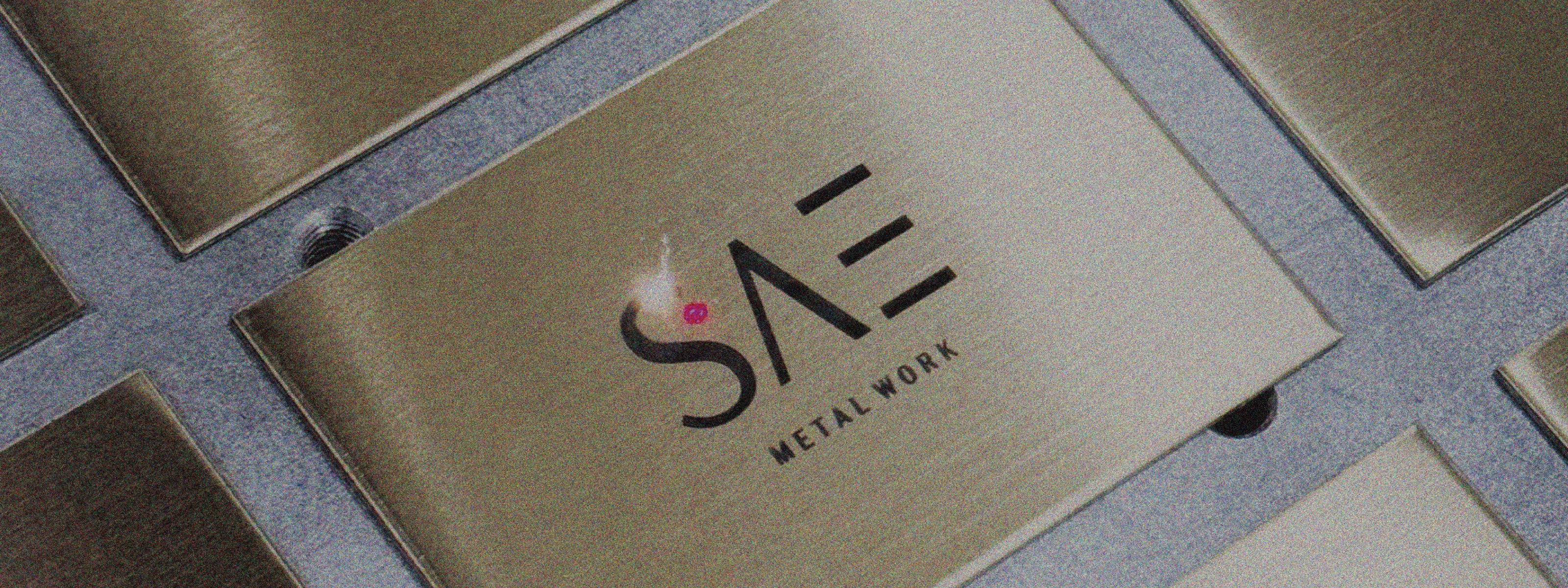 A top-down shot of SAE METAL WORK’s signature stainless-inlaid grid plate, capturing the precise geometric structure and craftsmanship that defines the brand’s design philosophy—where objects don’t speak, but say everything.